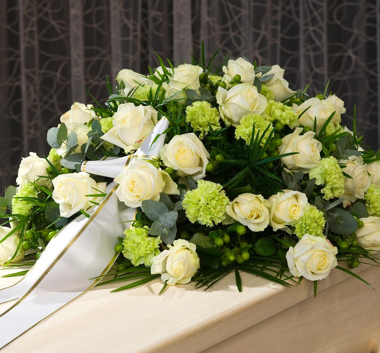 A standing spray with white roses, delphiniums, lilies, mini carnations and greens.